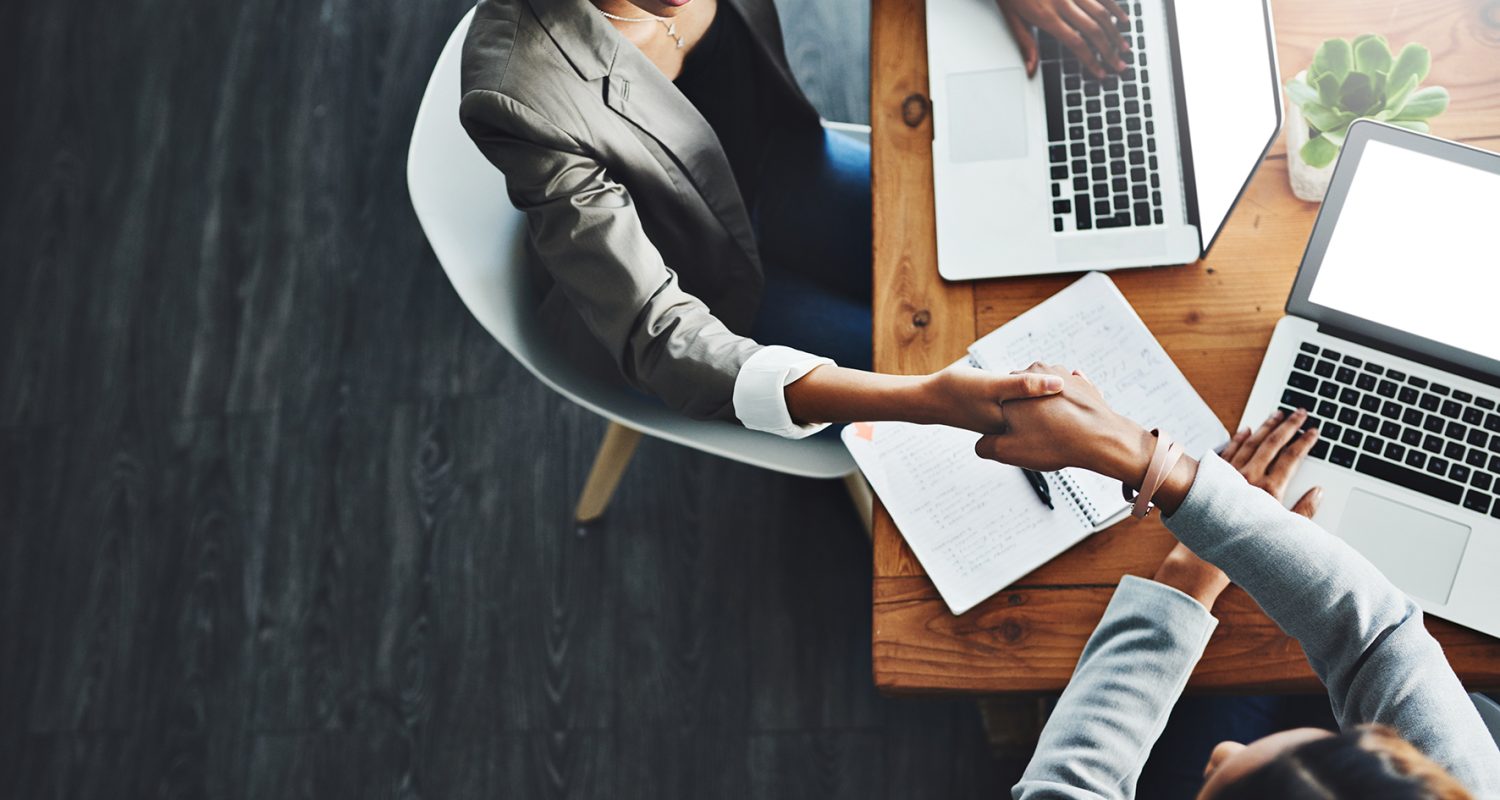 High angle shot of two businesswomen shaking hands in an office