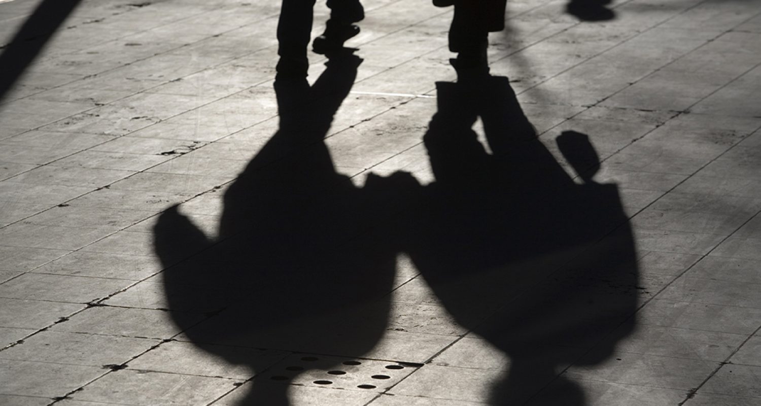 sun casting shadow over two people walking on the street sun casting shadow over two people walking on the street