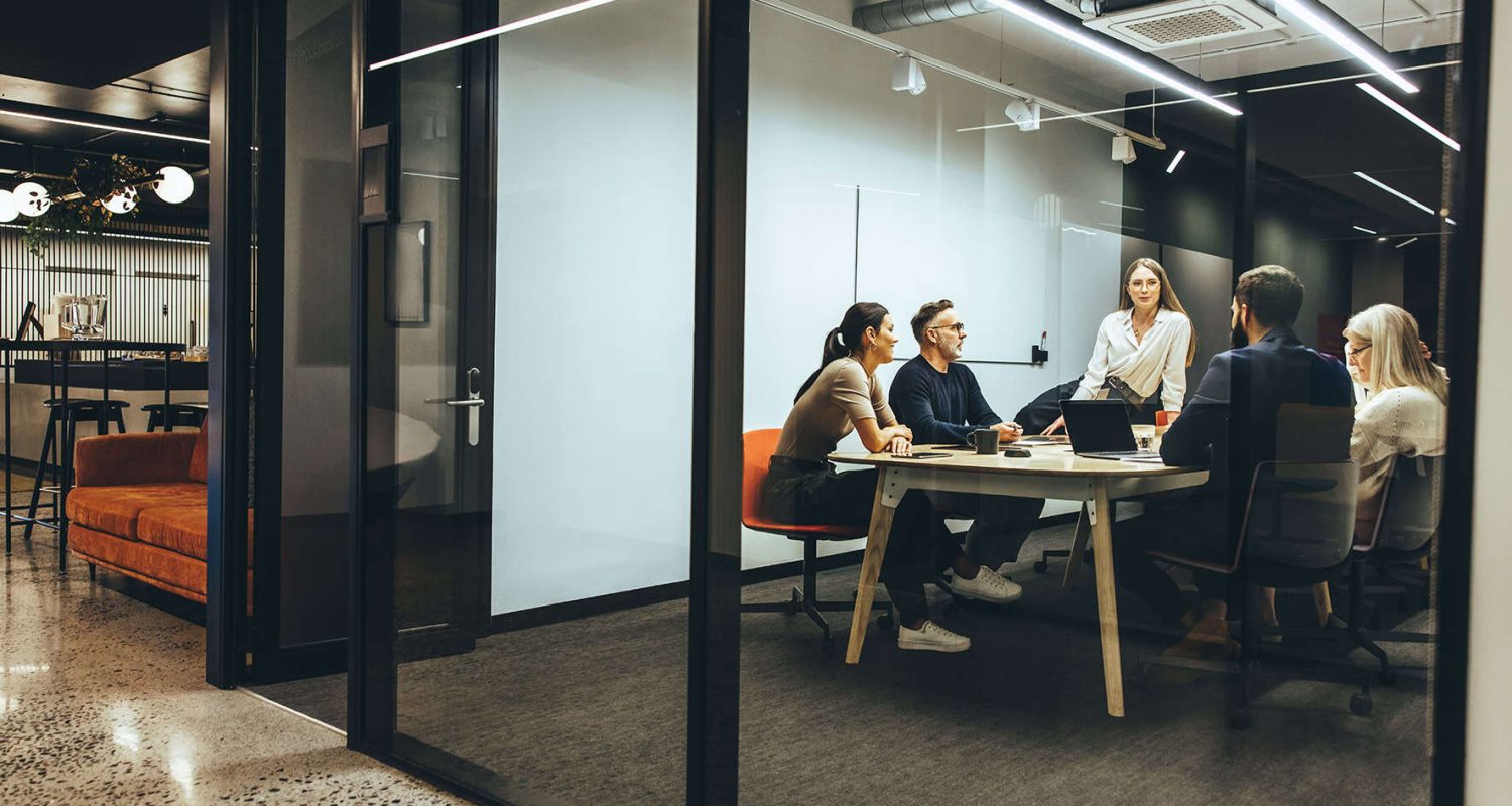 Team of diverse businesspeople having a meeting in a transparent boardroom. Group of business professionals having a discussion during a briefing. Colleagues collaborating on a new project.
